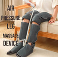 Gray air compression leg boots worn while seated on a sofa