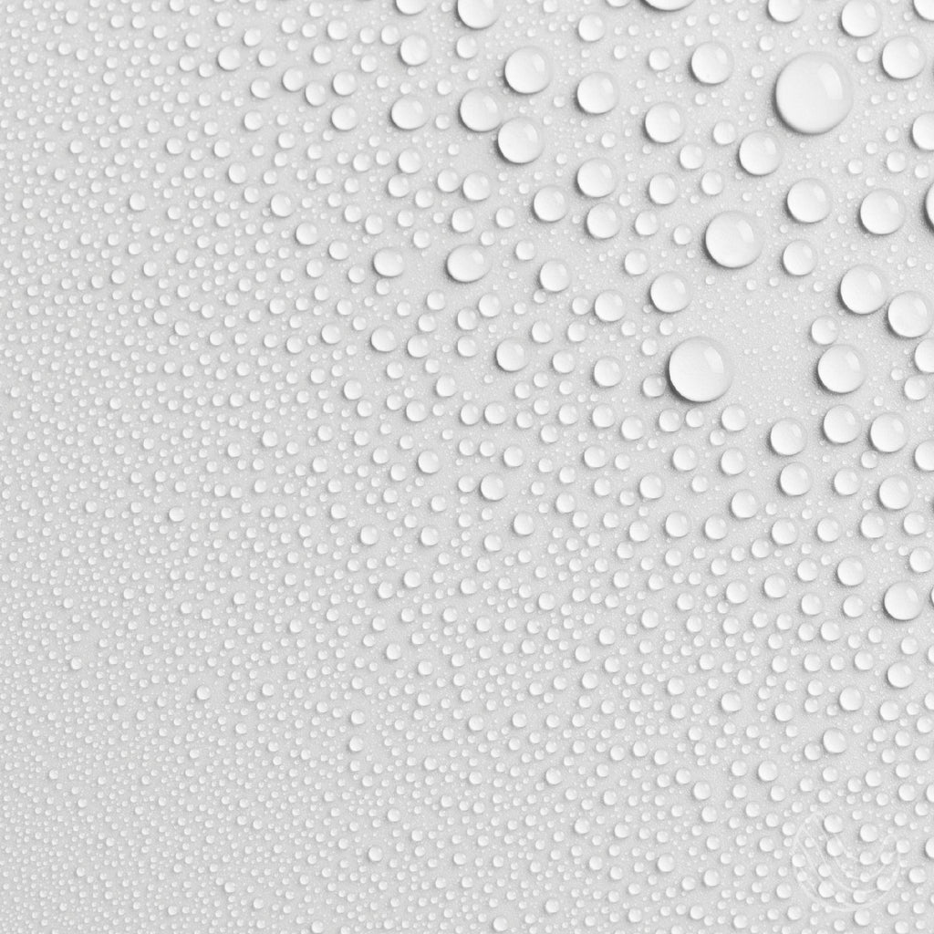 Fine water droplets on a white surface, showing the light mist of the Innatus pillow spray