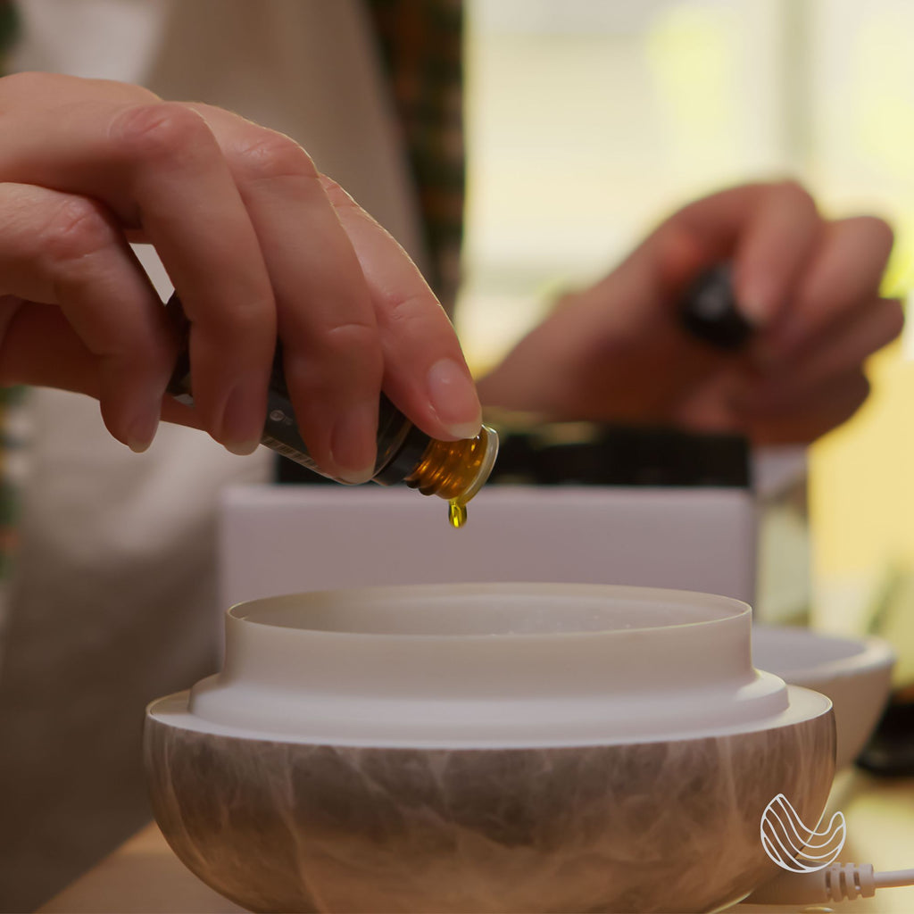 Hand adding drops of Innatus Dream essential oil to a diffuser