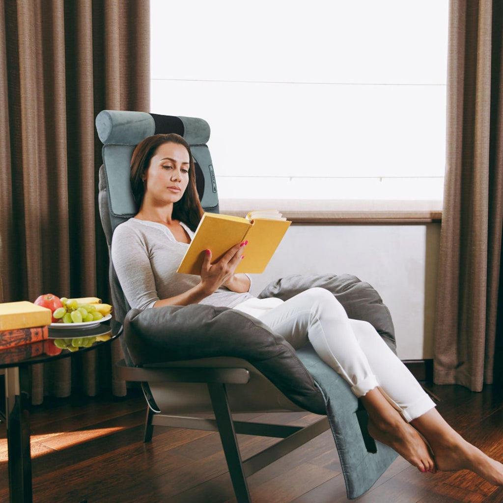 Woman reading in a recliner with the massage mat draped over it