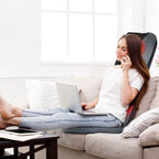 Woman using a laptop on a sofa with the massage cushion behind her