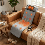 Gray massage mat draped over a leather armchair, its massage zones glowing, with the controller on the seat