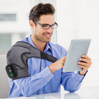 Man reading a tablet while wearing the gray shoulder wrap