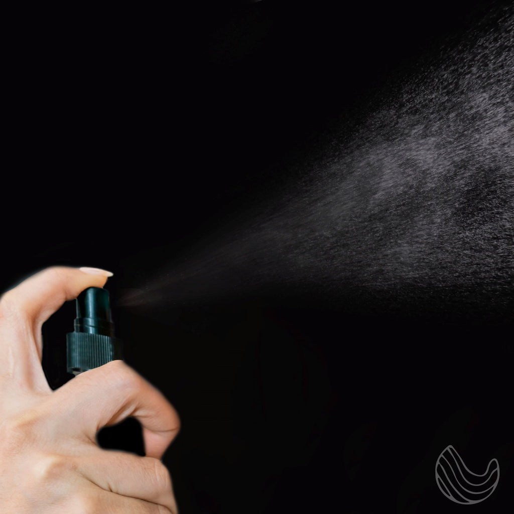 Hand spraying a fine mist from a small spray bottle